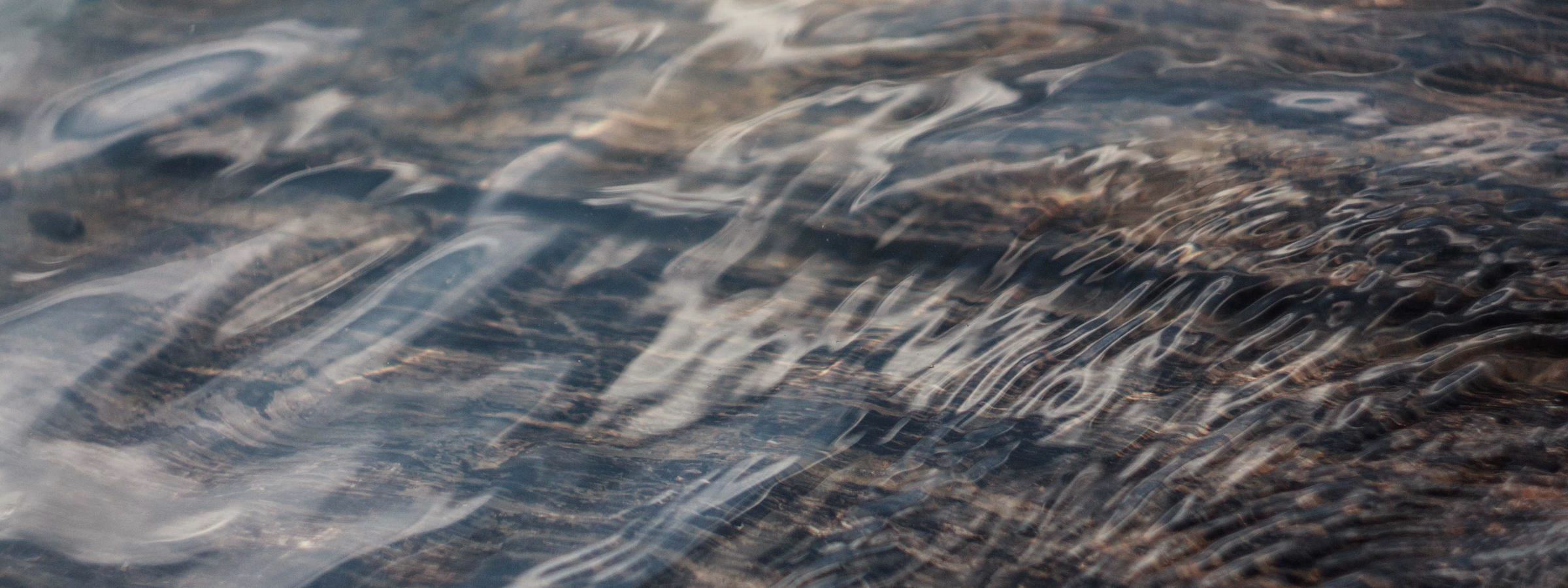 Dark water moving slowly under a grey sky