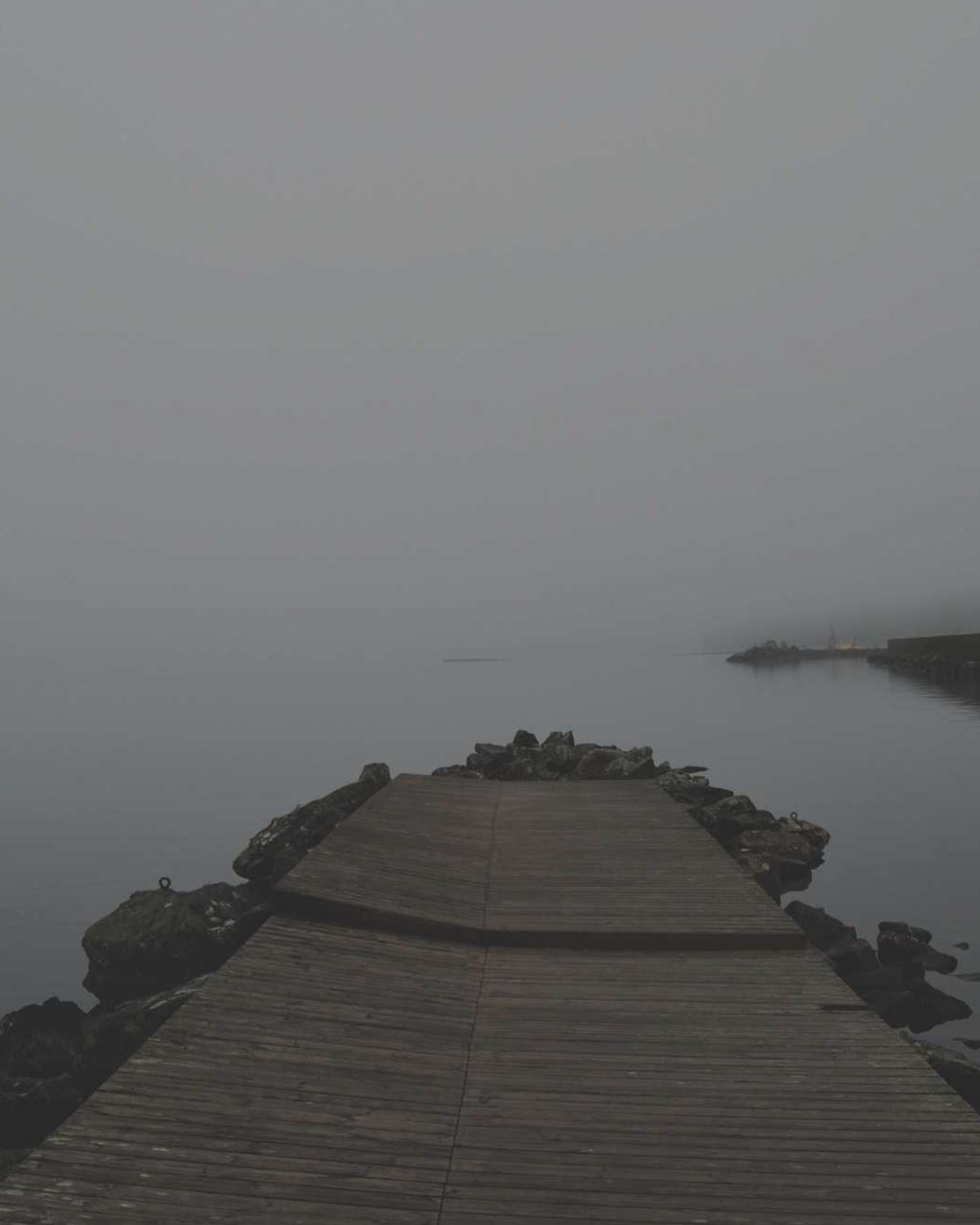 A quiet jetty reaching into a foggy lake