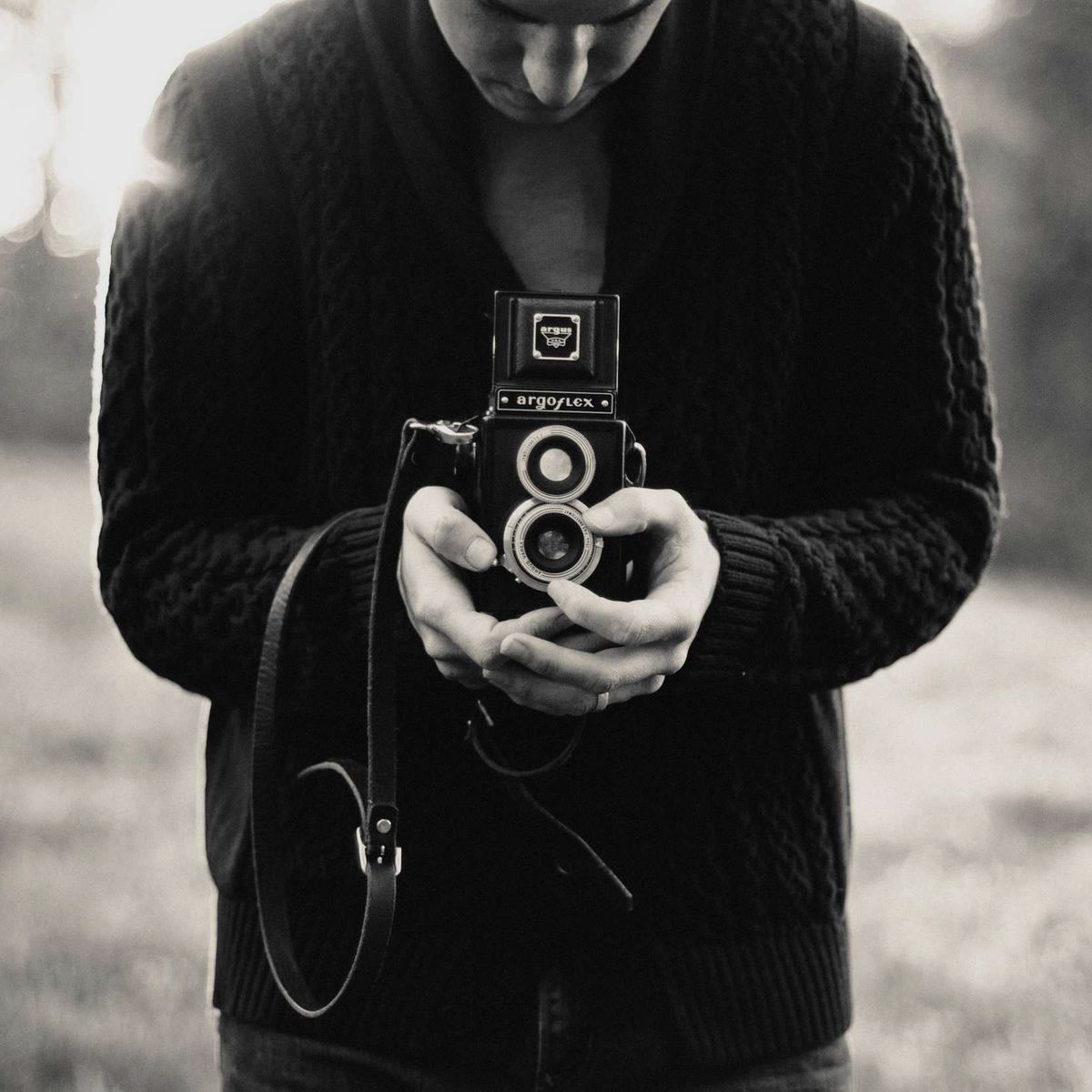 Black and white portrait of hands holding an old camera