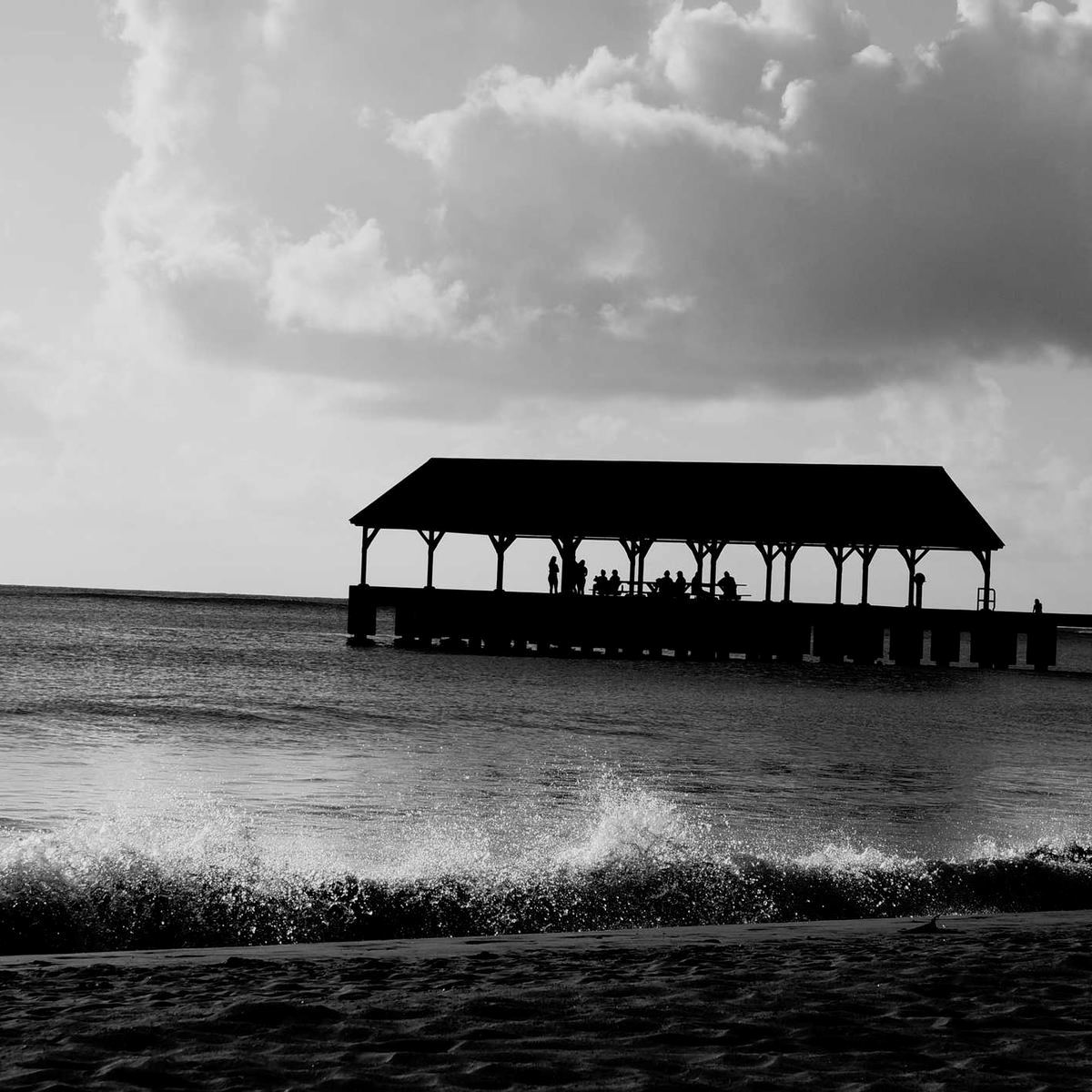 A wooden pier disappearing into fog over grey water